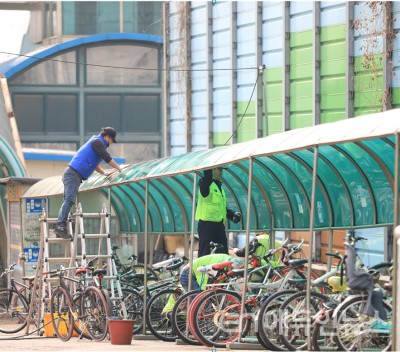 작업자가 화서역 앞 자전거 보관대를 세척하고 있다(사진제공=수원시)